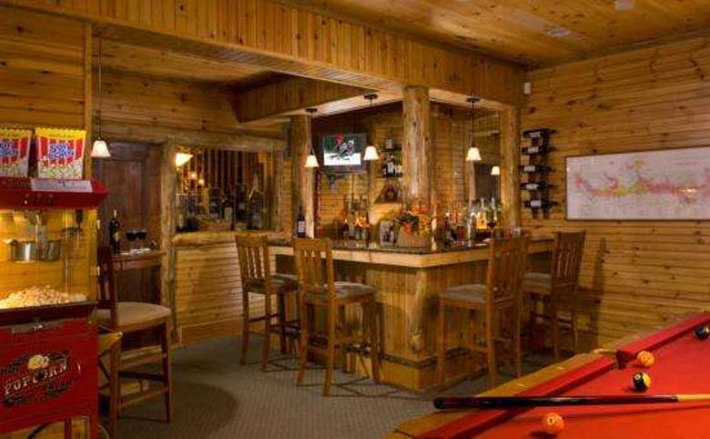 the bar area with a pool table and popcorn machine in a warm rustic lodge decor