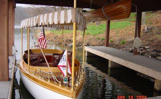 an electric boat with canopy and flags inside the boathouse