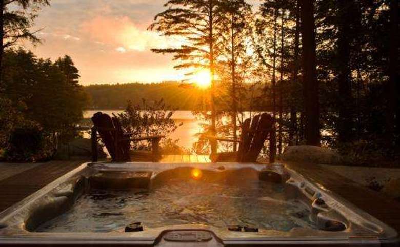 a sunrise over the lake with the outdoor hot tub bubbling