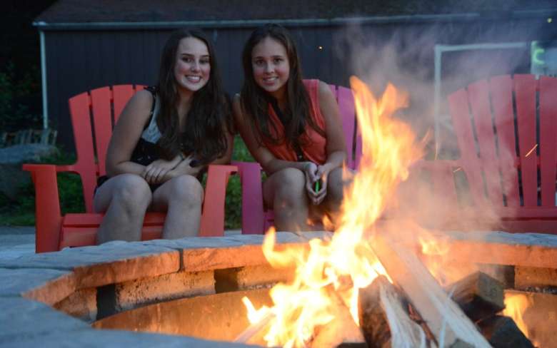 two young women by a campfire