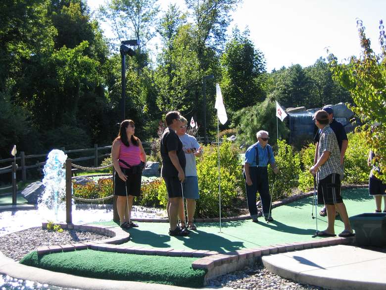 Family playing mini golf next to a water feature