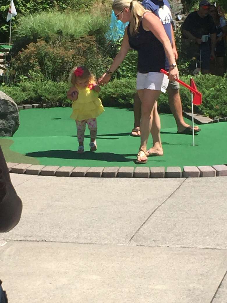 A young girl and her mom walking on a putting green