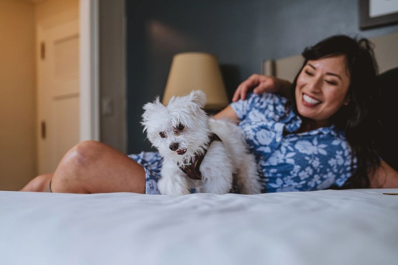 a woman relaxing with a white dog in bed