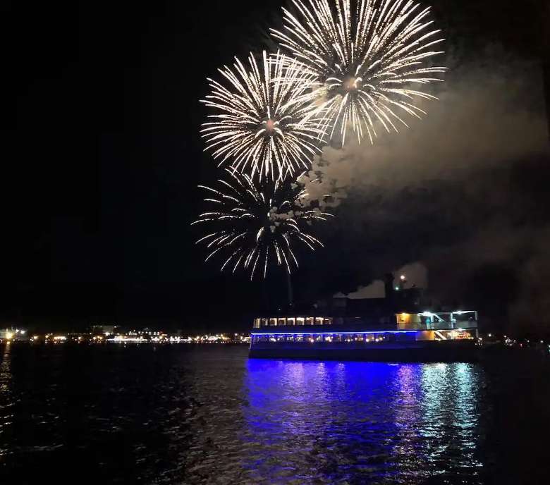 fireworks launching over a cruise ship on a lake