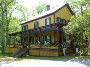 exterior of grant cottage, a mustard colored building with dark green shutters and dark brown accent trim