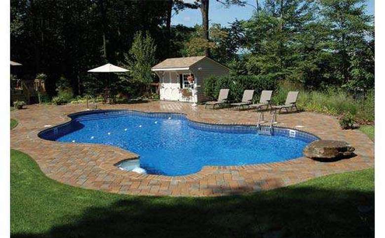 in-ground pool with four lounge chairs on the deck