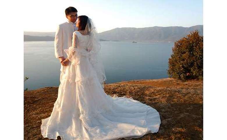 Bride and groom in front of a lake and surrounding mountains