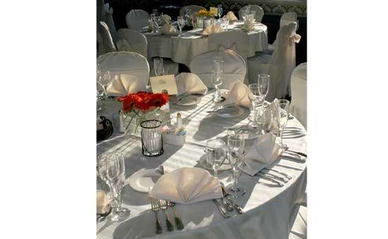 Tables set for a wedding, complete with silverware, linens, and centerpieces