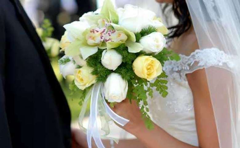 bride and groom partially obscured by a floral bouquet
