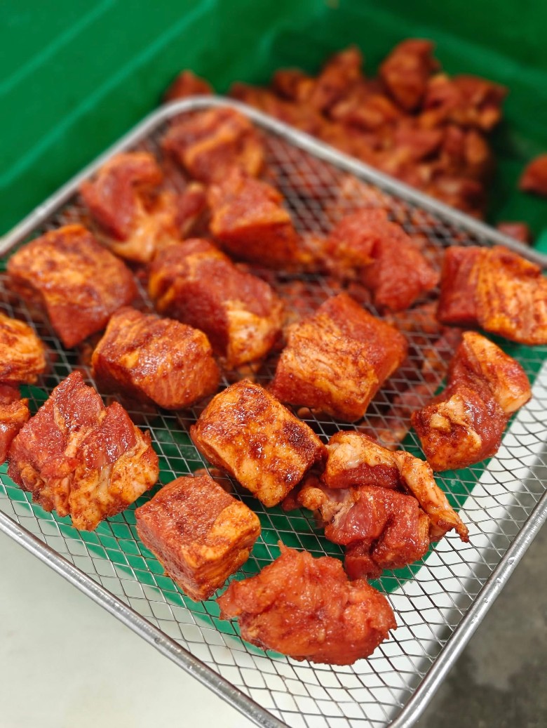 Cubed, marinated meat ready for smoking on a wire rack.