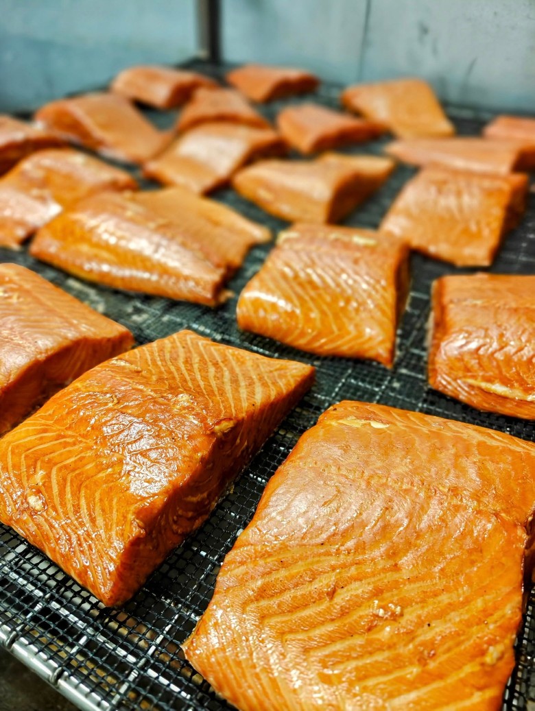 Numerous fillets of smoked salmon resting on a wire rack.