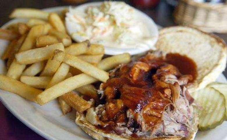 a pulled pork sandwich, french fries, and cole slaw on a plate