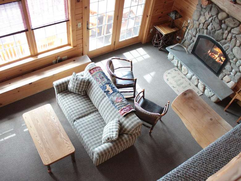 looking down from upstairs into a quaint living room with stone fireplace
