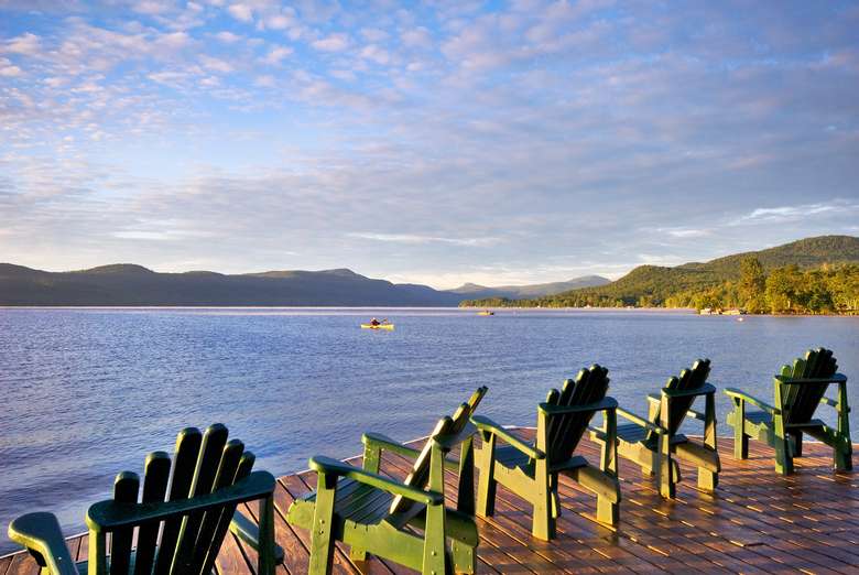 green Adirondack chairs lined up facing the lake