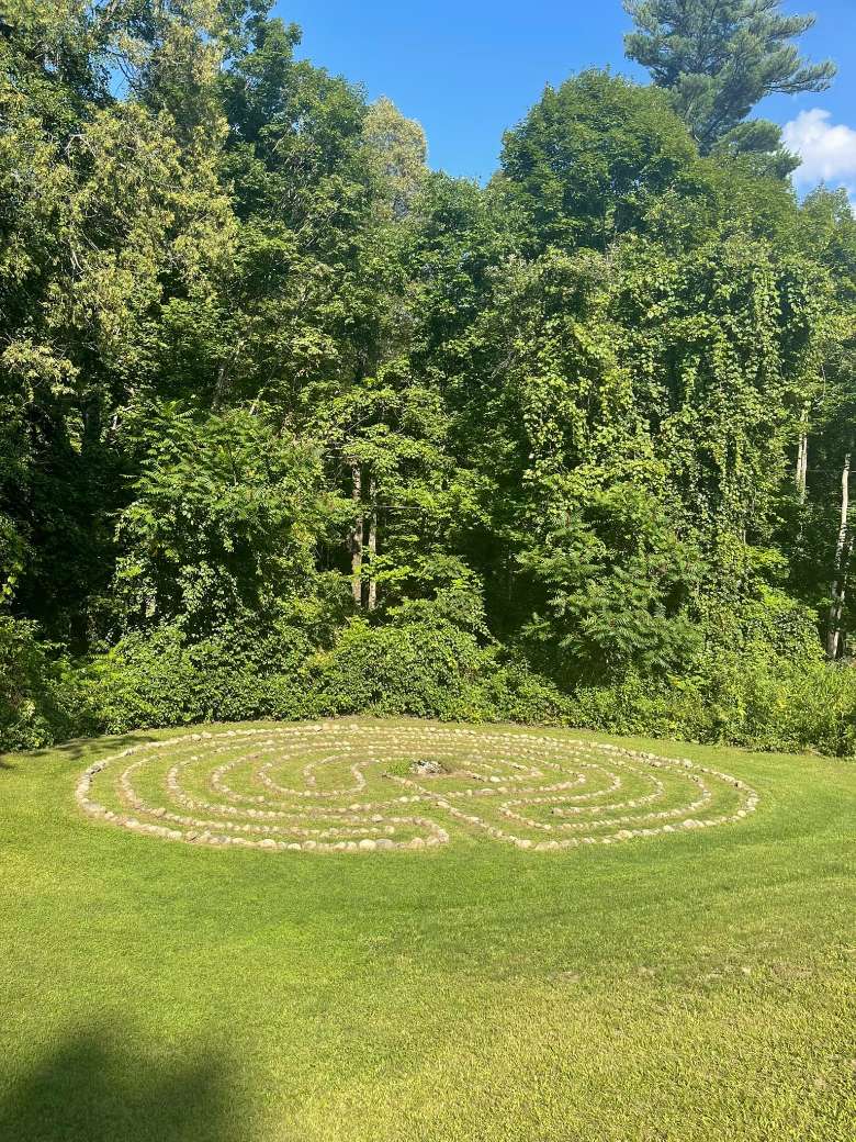 a stone labyrinth on a grassy lawn with trees out back