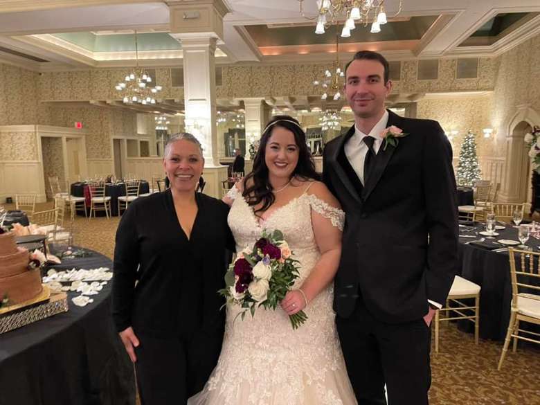 bride, groom, and female wedding officiant indoors