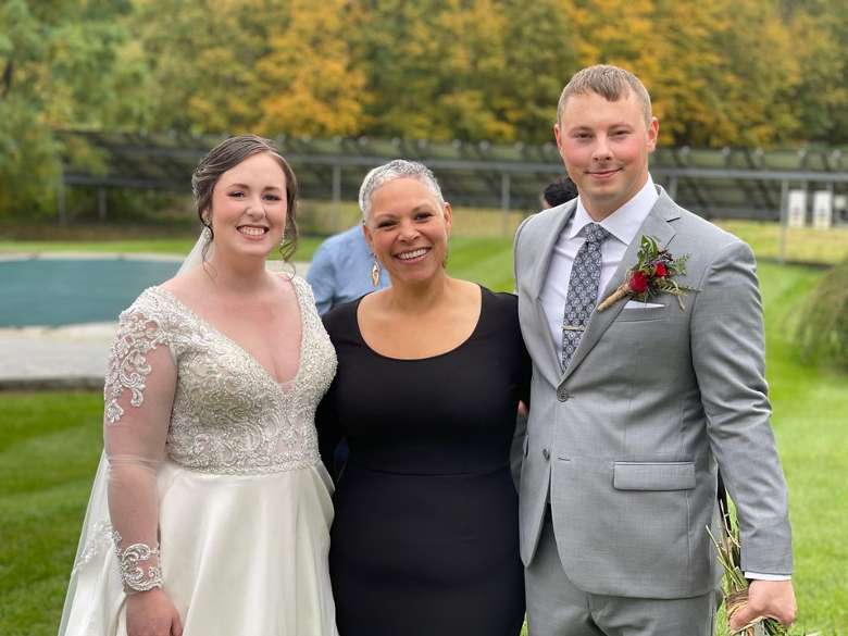 bride, groom, and female wedding officiant outdoors