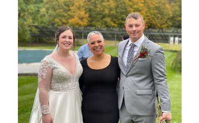 bride, groom, and female wedding officiant outdoors
