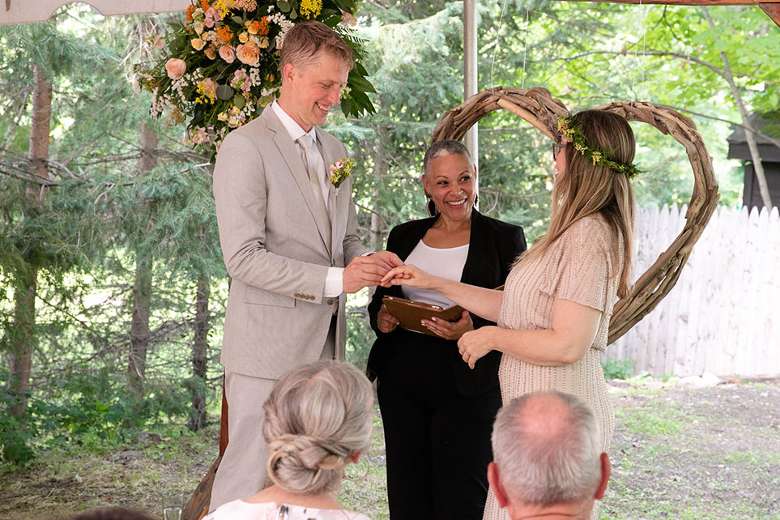 bride, groom, and female wedding officiant outdoors near heart shaped display