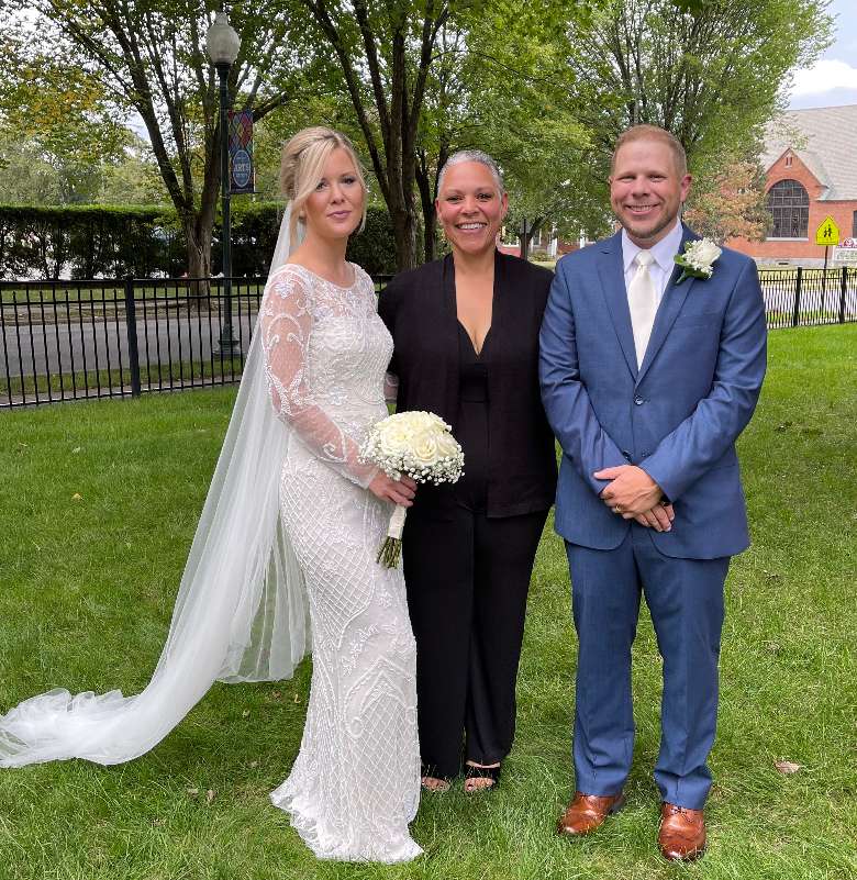 female wedding officiant standing with bride and groom
