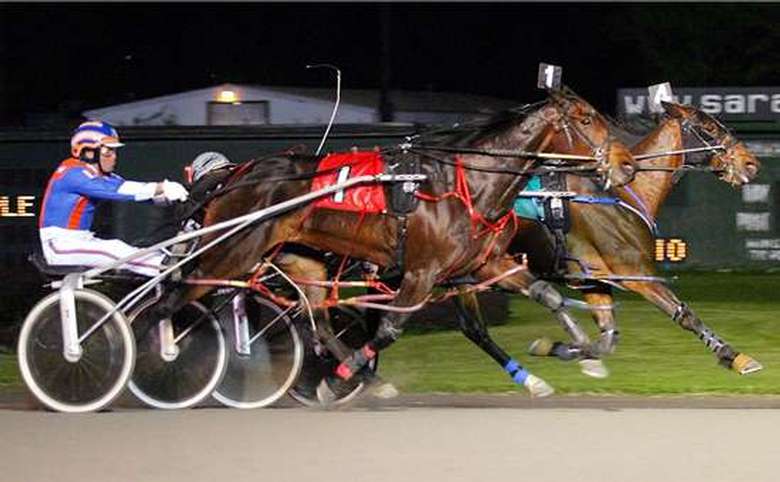 two horses and riders competing in harness racing