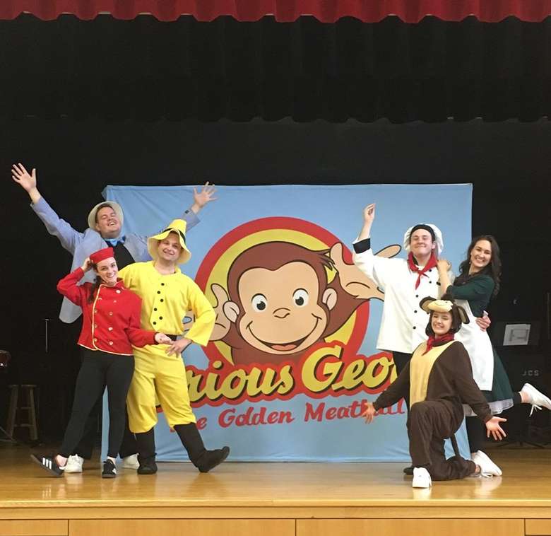 people on stage with curious George backdrop