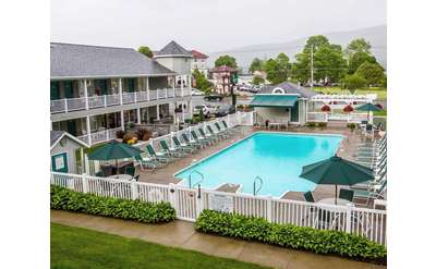 The exterior of the Quality Inn - Lake George, showing the inground pool, surrounding pool deck, and some of the rooms.