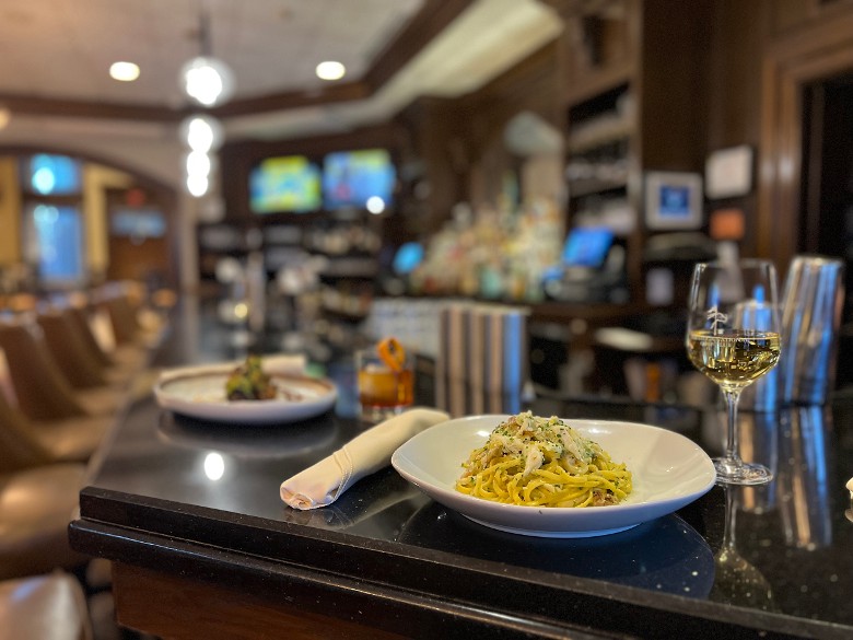 wine glass and plates of food on a bar