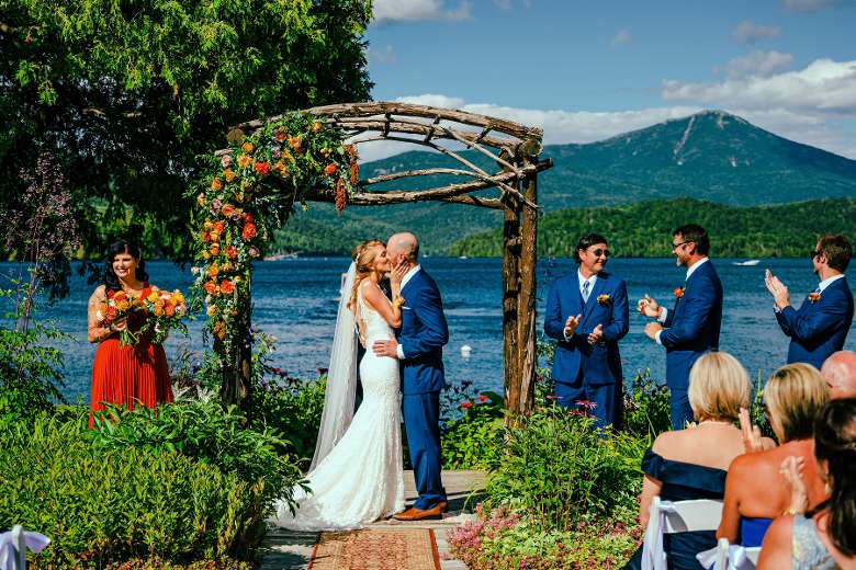 bride and groom kiss in front of alter and lake
