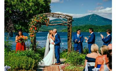 bride and groom kiss in front of alter and lake