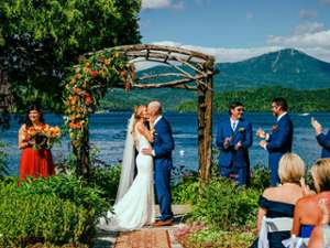 bride and groom kiss in front of alter and lake