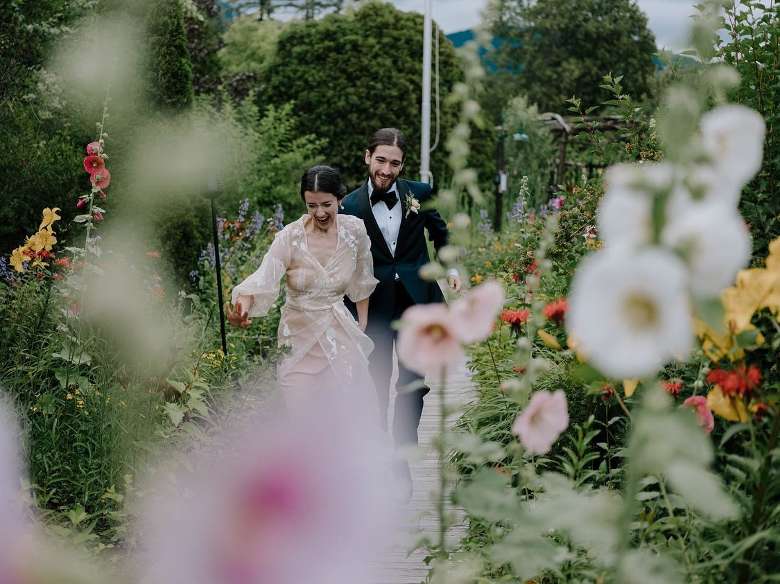 bride and groom run through garden