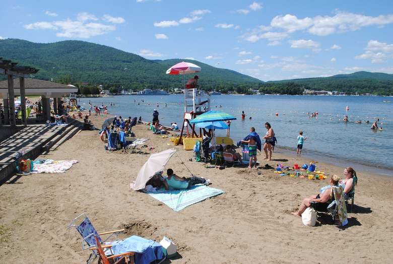 lifeguard chair and people on the sandy beach in lake george