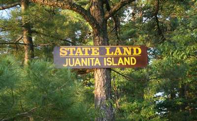 the sign for the juanita island state land on a tree