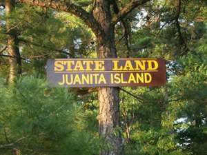 the sign for the juanita island state land on a tree