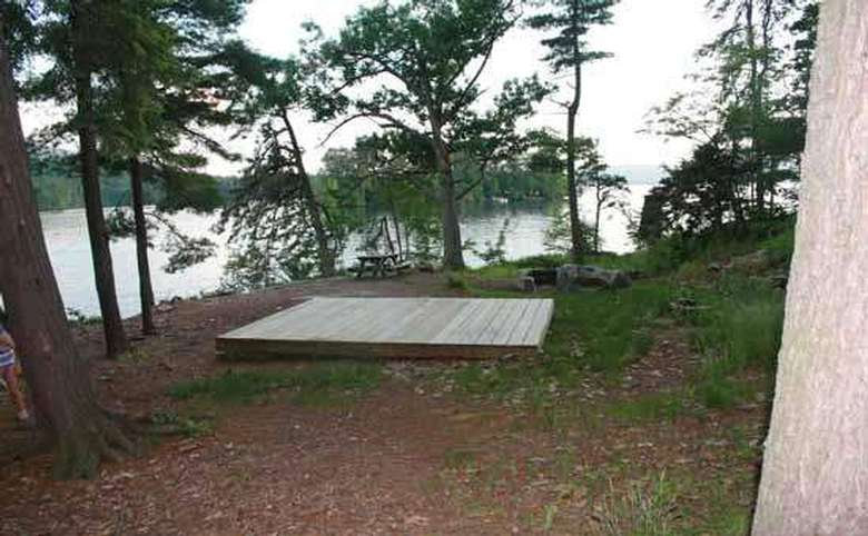 a large and wooden tent platform on flat ground in the woods