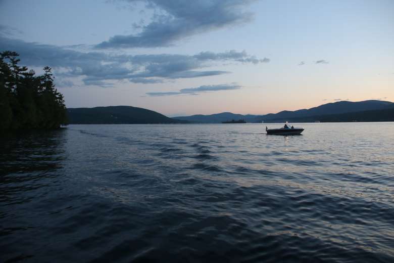 people boating on a lake when the sun is mostly gone