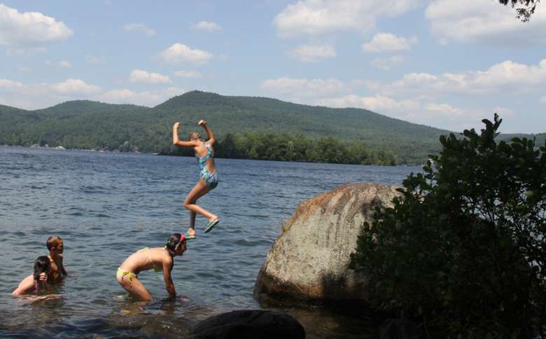 people jumping from a small rock in the water