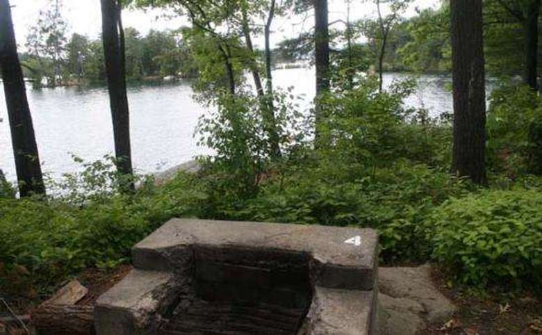 a firepit at a campsite with the lake in the background