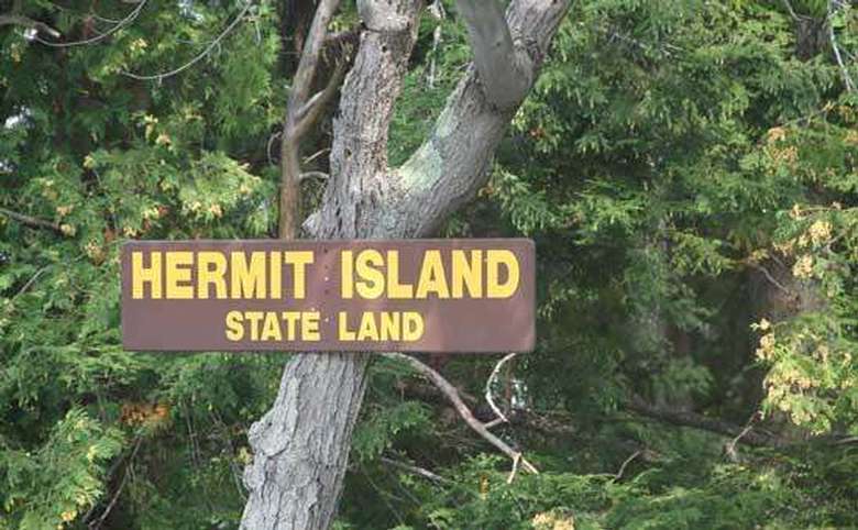 the sign for hermit island state land on a tree