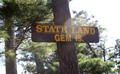 a sign for gem island on a tree