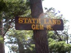 a sign for gem island on a tree