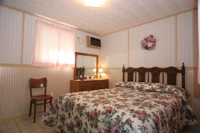 a bed with a floral blanket, light pink curtians on window