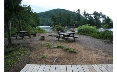 a campground area with a tent platform and two picnic tables