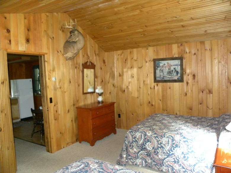 a rustic cabin room with two beds and a dresser
