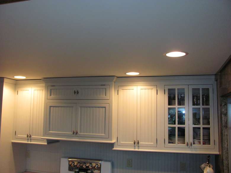 lights on the ceiling shining on upper kitchen cabinets