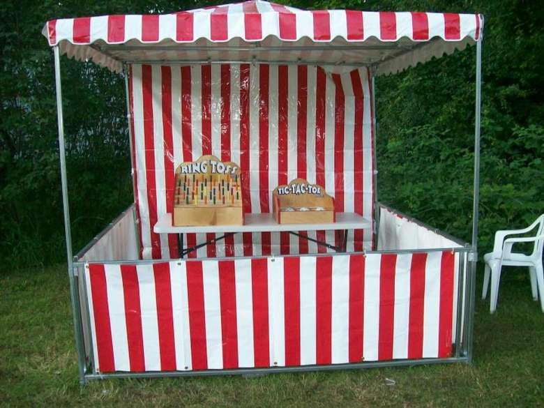 A red and white striped booth with ring toss and tic-tac-toe games