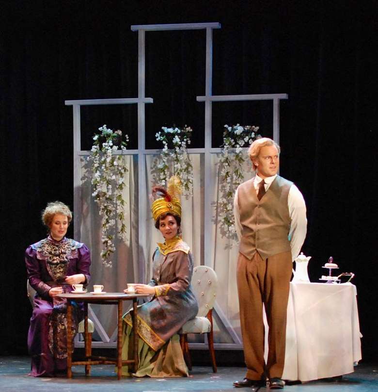 three people on stage, two sitting at a table