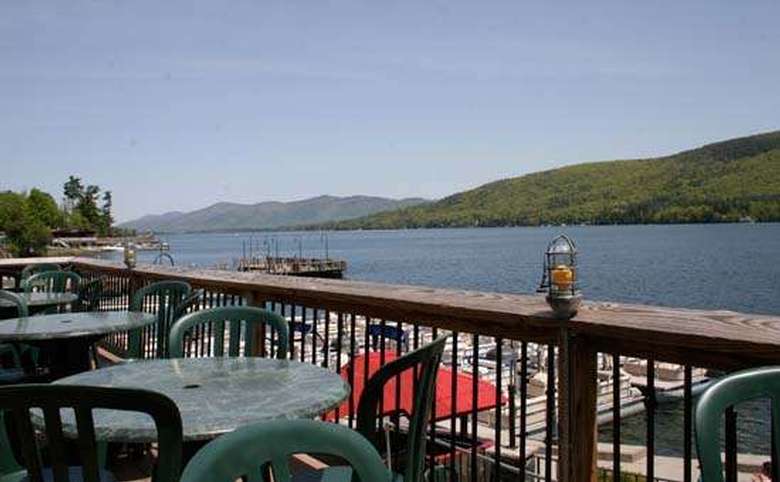Lake George as seen from the deck of Christie's. There are a couple tables in the foreground, and mountains in the background.