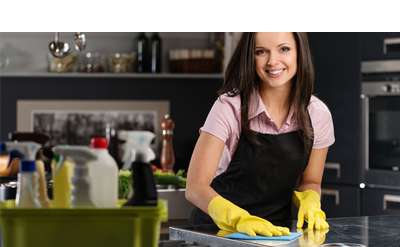 a woman with dish gloves cleaning a kitchen countertop